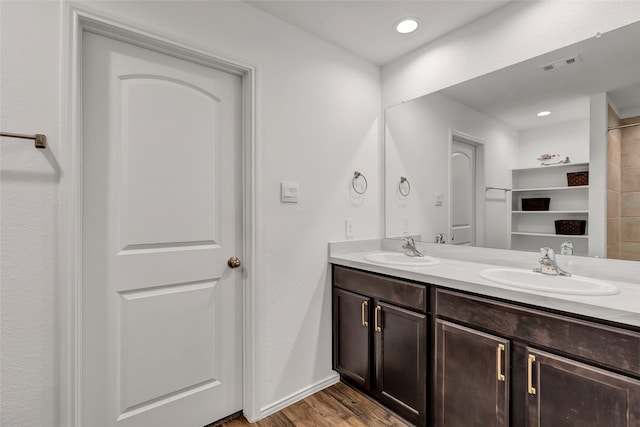 bathroom with a sink, visible vents, wood finished floors, and double vanity