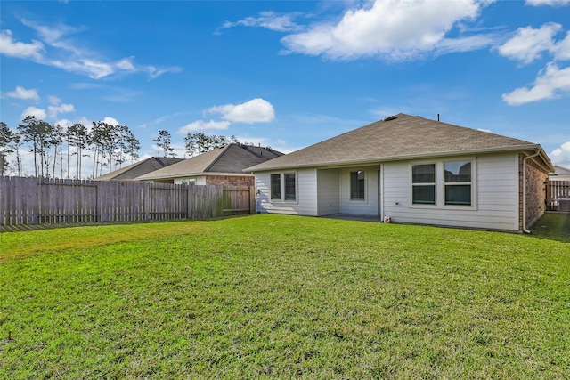 rear view of property featuring brick siding, a fenced backyard, a lawn, and roof with shingles