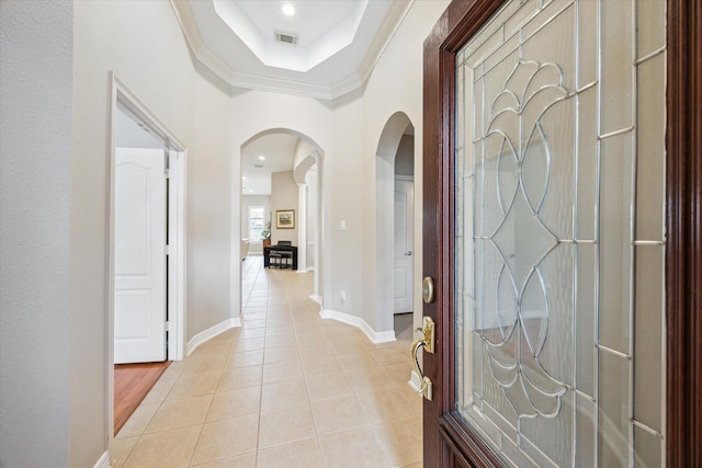 entryway featuring visible vents, a tray ceiling, arched walkways, light tile patterned floors, and baseboards