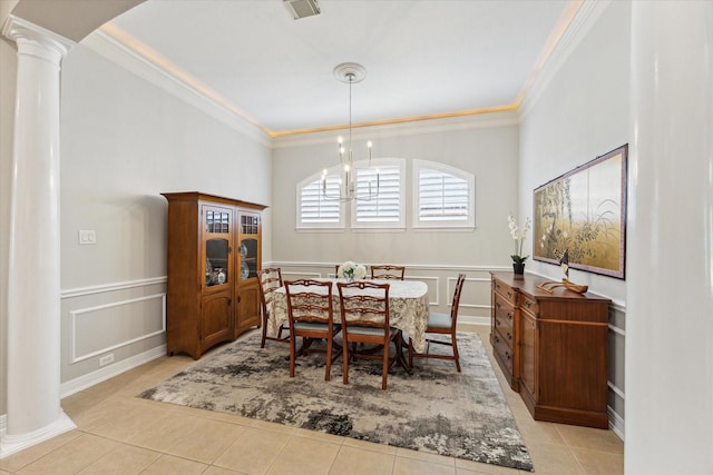 dining room featuring a wainscoted wall, ornamental molding, light tile patterned flooring, a decorative wall, and ornate columns