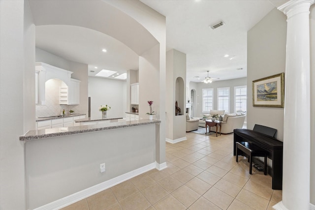 kitchen featuring visible vents, white cabinetry, light tile patterned floors, decorative backsplash, and light stone countertops