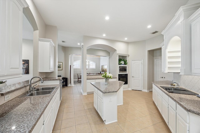 kitchen with black appliances, arched walkways, visible vents, and a sink