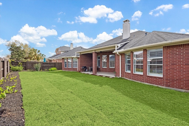 rear view of property with a patio, a fenced backyard, a chimney, a lawn, and brick siding