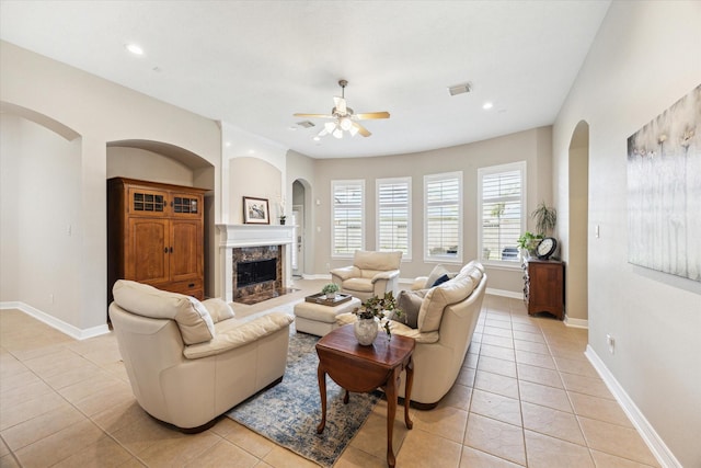 living area with light tile patterned floors, visible vents, arched walkways, and a ceiling fan