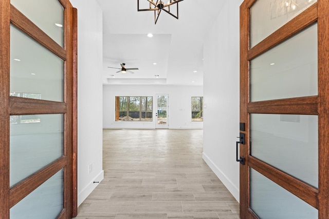 hallway with recessed lighting, baseboards, a notable chandelier, and light wood finished floors