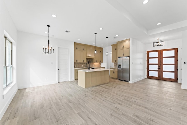 kitchen featuring open floor plan, light countertops, stainless steel refrigerator with ice dispenser, and an inviting chandelier