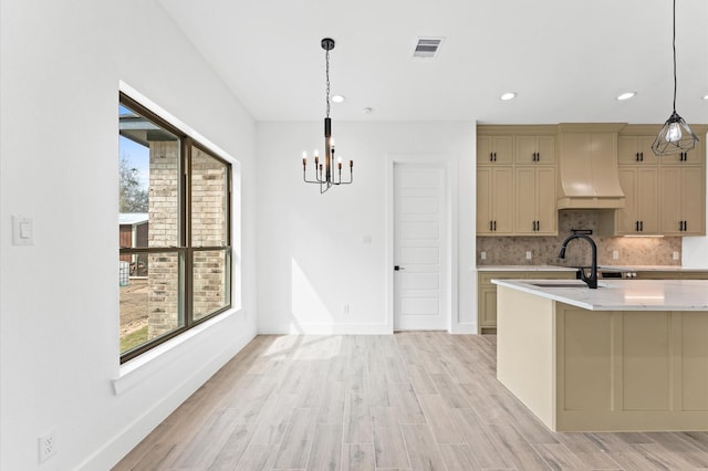 kitchen with light wood finished floors, plenty of natural light, custom exhaust hood, and tasteful backsplash