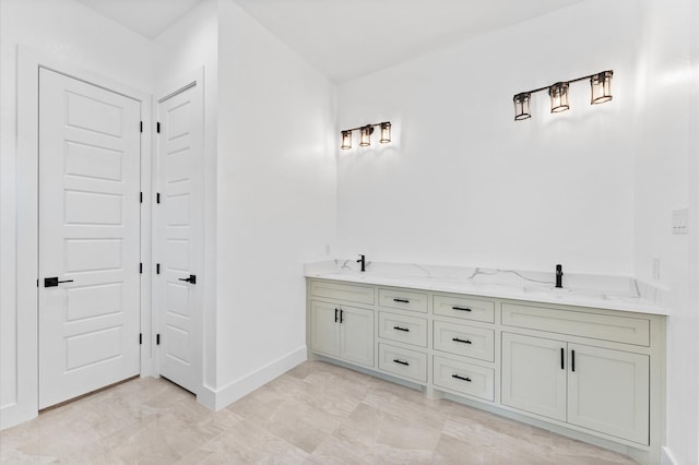 bathroom with double vanity, baseboards, and a sink