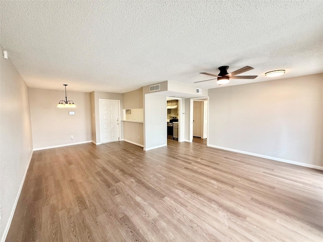 unfurnished living room with wood finished floors, visible vents, baseboards, and ceiling fan with notable chandelier