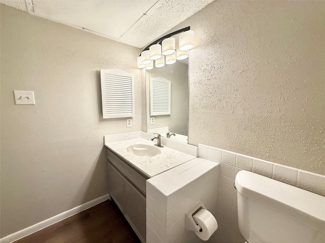 bathroom featuring a textured wall, toilet, wood finished floors, visible vents, and vanity