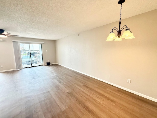 unfurnished room with a textured ceiling, baseboards, wood finished floors, and ceiling fan with notable chandelier