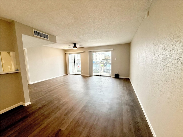 spare room featuring a textured ceiling, wood finished floors, visible vents, and baseboards