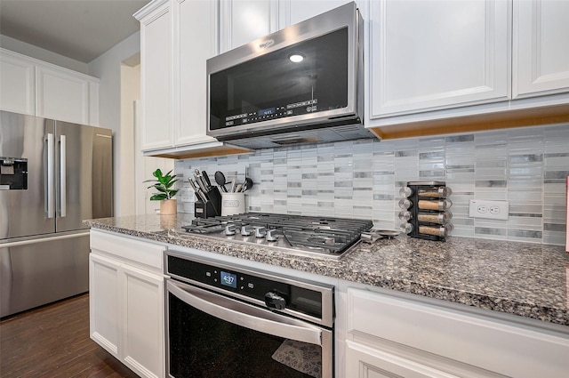 kitchen featuring dark stone countertops, appliances with stainless steel finishes, white cabinets, and backsplash