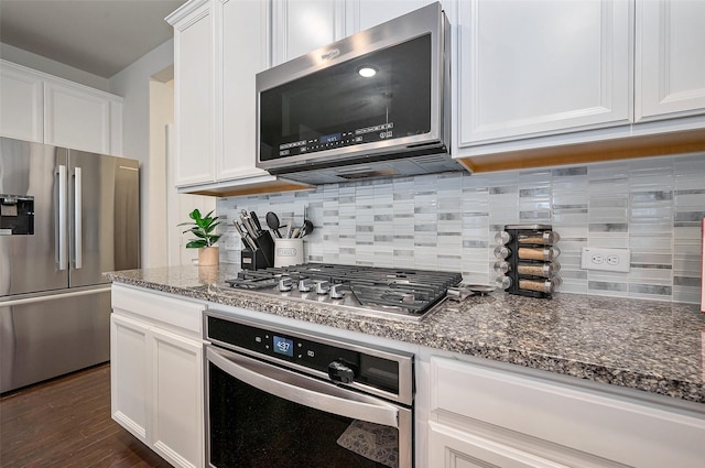 kitchen featuring white cabinetry, stainless steel appliances, and dark stone countertops