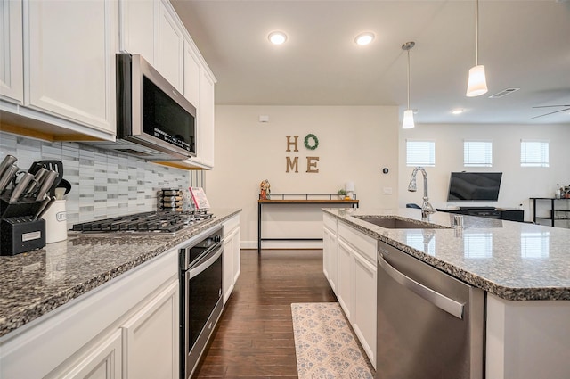 kitchen with dark wood finished floors, stainless steel appliances, visible vents, backsplash, and a sink