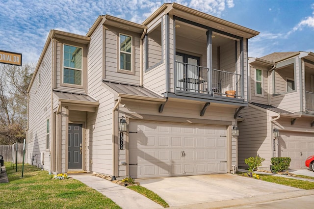 townhome / multi-family property with a garage, a balcony, driveway, metal roof, and a standing seam roof