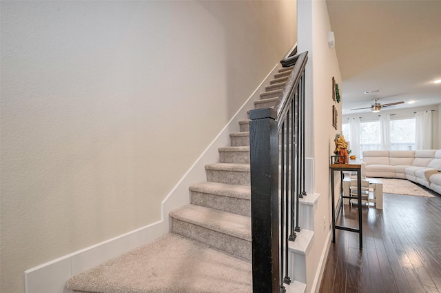 stairs with wood-type flooring, a ceiling fan, and baseboards