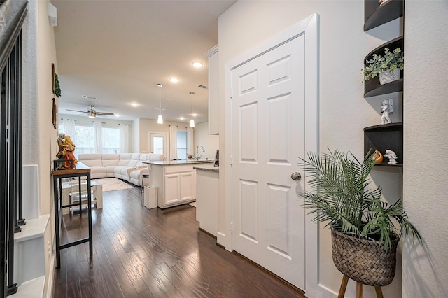hall with recessed lighting, dark wood-style flooring, and a sink