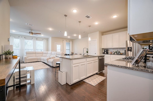 kitchen with light stone counters, visible vents, a sink, and white cabinetry