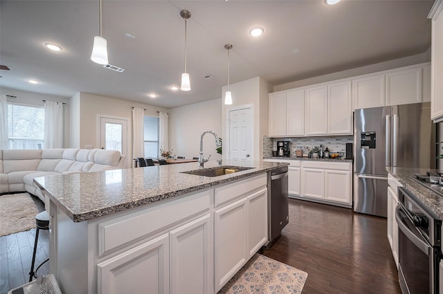 kitchen featuring stainless steel appliances, dark wood-style flooring, a sink, visible vents, and backsplash