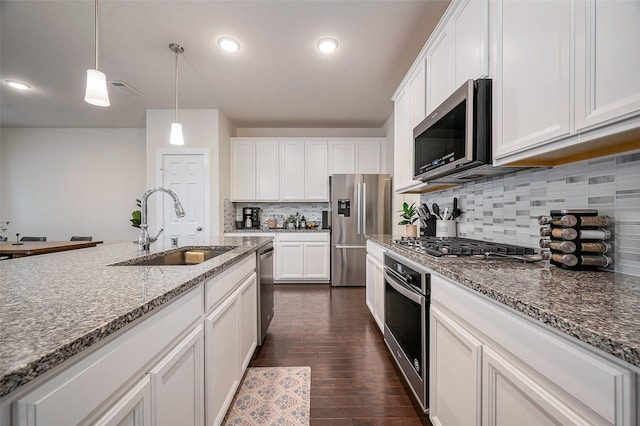 kitchen with dark wood-style floors, decorative light fixtures, stainless steel appliances, white cabinetry, and a sink