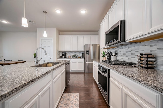 kitchen with white cabinets, a sink, tasteful backsplash, decorative light fixtures, and appliances with stainless steel finishes