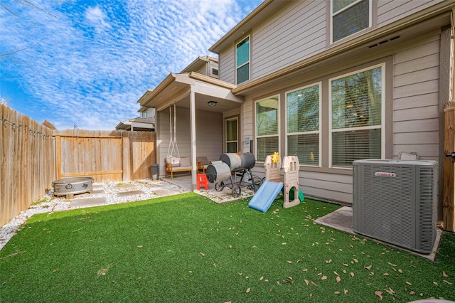 back of property featuring central air condition unit, a fenced backyard, a lawn, and a patio