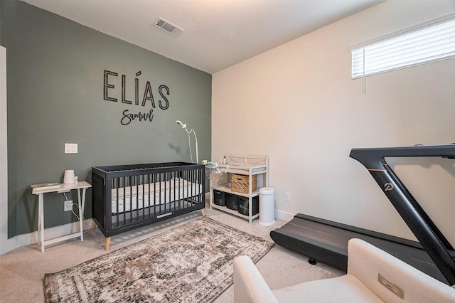 carpeted bedroom featuring a crib, visible vents, and baseboards