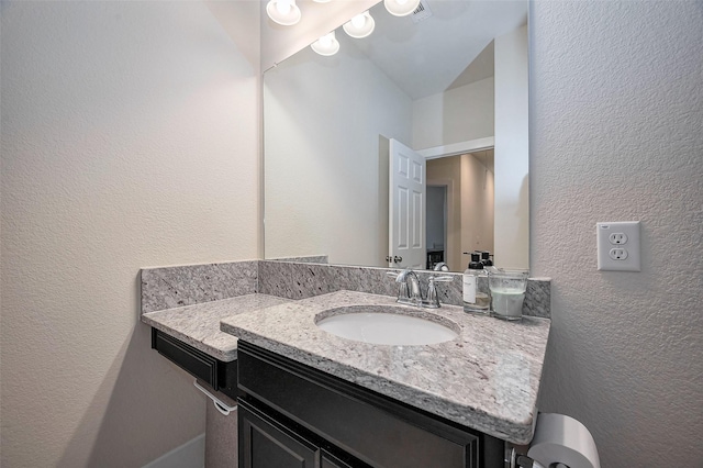 bathroom featuring vanity, visible vents, and a textured wall