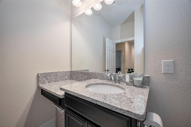 bathroom with a textured wall and vanity