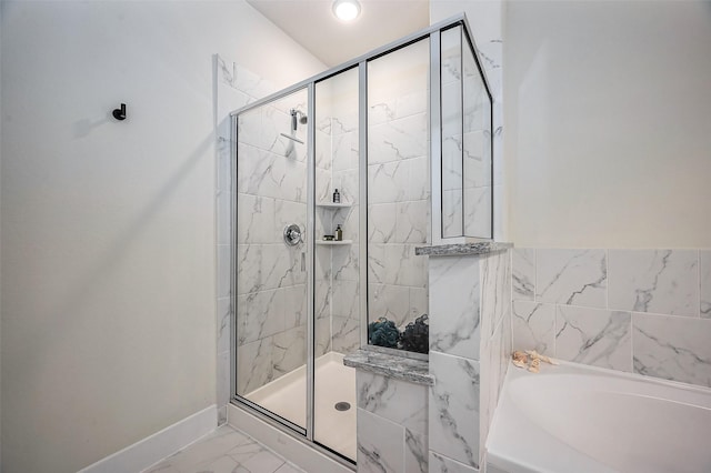 full bath with marble finish floor, baseboards, a garden tub, and a stall shower