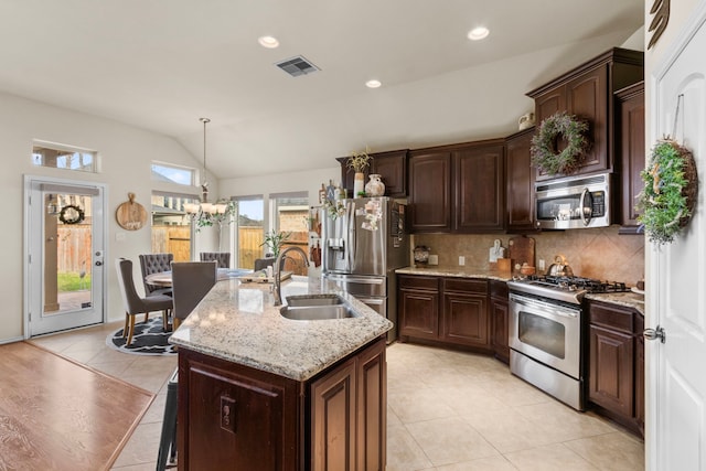 kitchen featuring stainless steel appliances, a sink, visible vents, vaulted ceiling, and tasteful backsplash