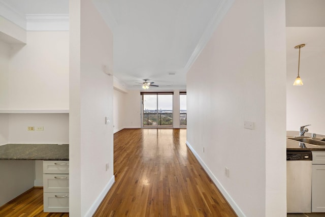 corridor with baseboards, hardwood / wood-style floors, a sink, and crown molding