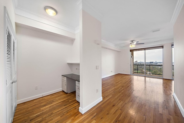 unfurnished living room with ornamental molding, built in study area, hardwood / wood-style floors, and baseboards