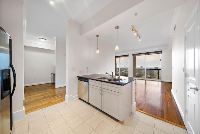 kitchen featuring dark countertops, appliances with stainless steel finishes, open floor plan, a sink, and light tile patterned flooring