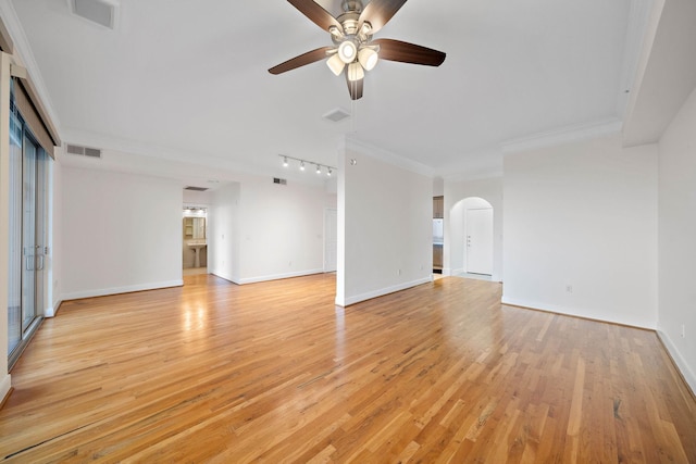 unfurnished living room with arched walkways, light wood-style flooring, visible vents, baseboards, and ornamental molding