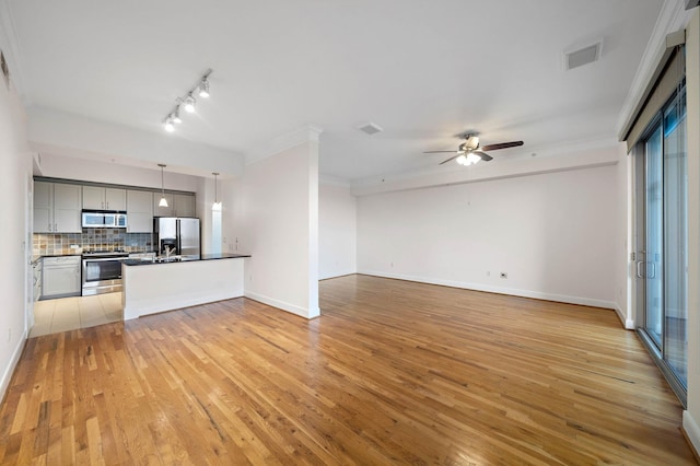 kitchen featuring stainless steel appliances, dark countertops, visible vents, light wood-style flooring, and decorative backsplash