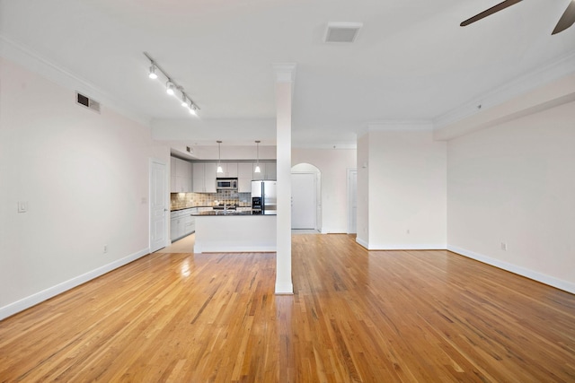 unfurnished living room featuring baseboards, visible vents, ceiling fan, light wood-style flooring, and crown molding