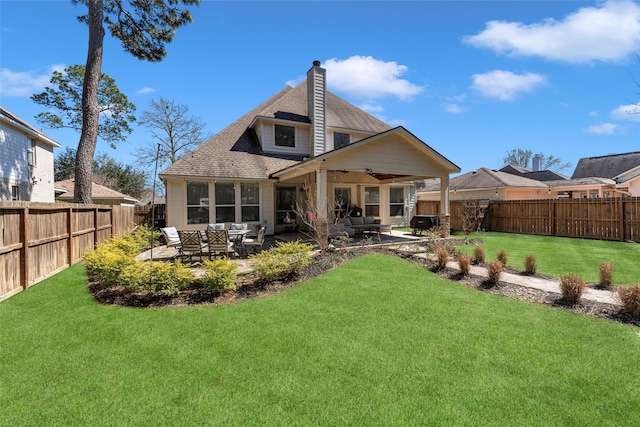 back of property featuring a chimney, a lawn, a patio area, and a fenced backyard