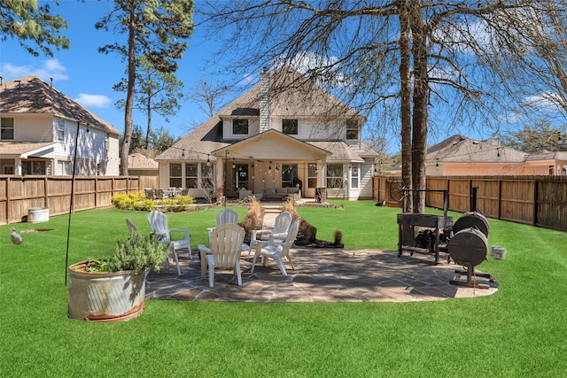 rear view of house featuring a yard, a fenced backyard, and a patio