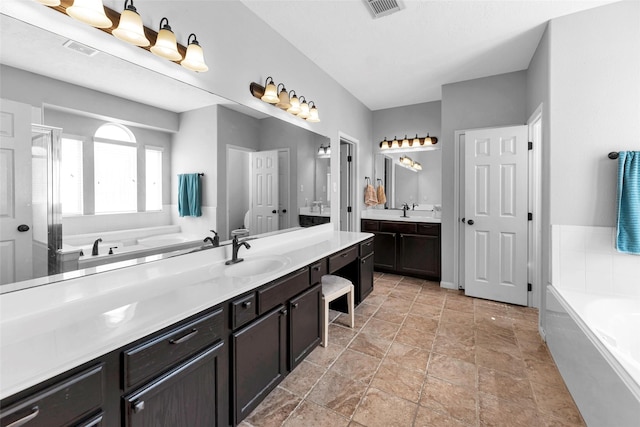 bathroom featuring two vanities, visible vents, a sink, and a garden tub