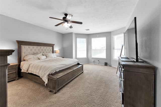 bedroom with baseboards, visible vents, a ceiling fan, light colored carpet, and a textured ceiling