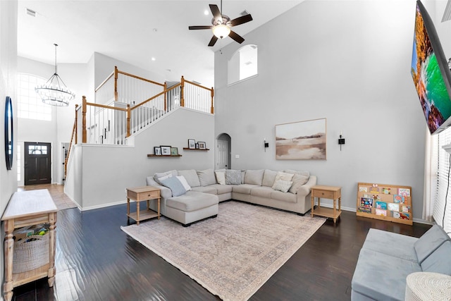 living area featuring stairway, baseboards, arched walkways, and wood finished floors