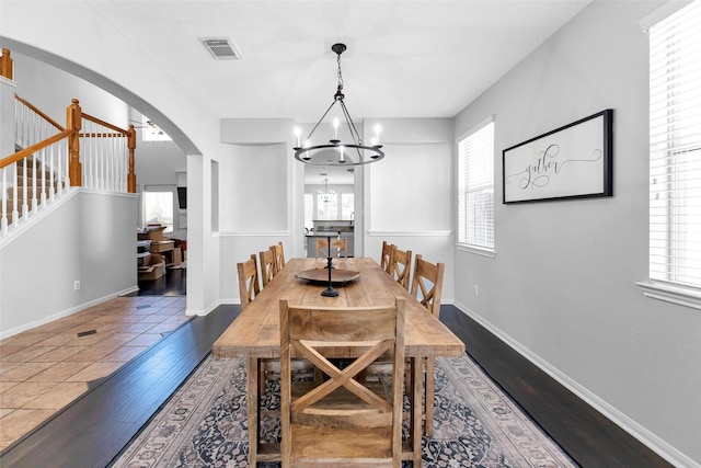 dining space featuring a chandelier, arched walkways, a healthy amount of sunlight, and wood finished floors