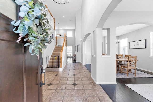 entryway featuring arched walkways, light tile patterned flooring, stairway, and baseboards