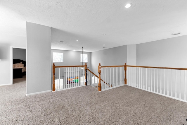 carpeted empty room featuring baseboards, visible vents, a textured ceiling, and recessed lighting