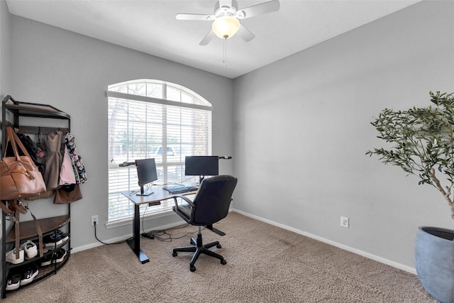 carpeted office space with a ceiling fan and baseboards