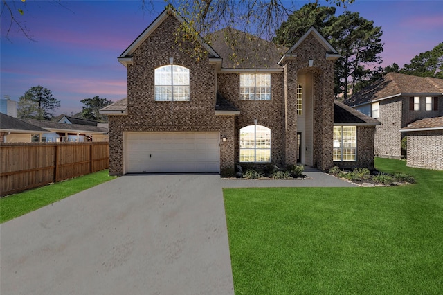 view of front facade featuring brick siding, concrete driveway, a lawn, an attached garage, and fence