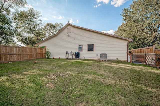 rear view of property with a fenced backyard, central AC unit, and a lawn