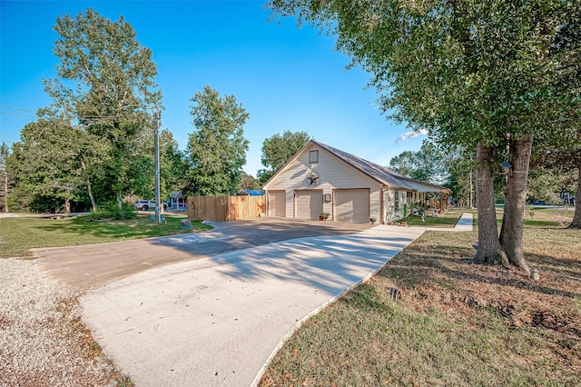 view of front of home with a garage, a front yard, concrete driveway, and fence